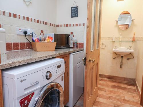 a kitchen with a washing machine and a sink at Ash Farm Cottage in Holywell