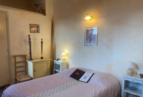 a bedroom with a bed with a book on it at Hôtel le Dauphin in Moulins-la-Marche