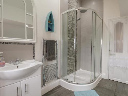 a white bathroom with a shower and a sink at Reighton House in Filey