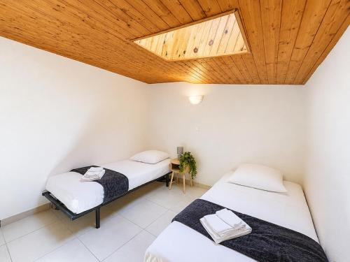 two beds in a room with a wooden ceiling at Le Côte-Rôtie in Vérin