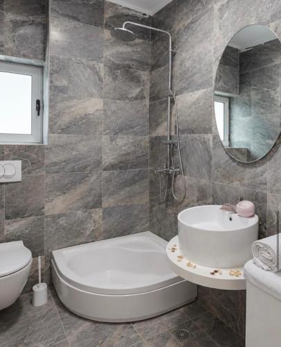 a bathroom with a tub and a sink and a toilet at Sun House in Kumbor