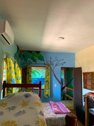 a bedroom with a bed and a tree mural on the wall at Pousada Conexão in Itaúnas