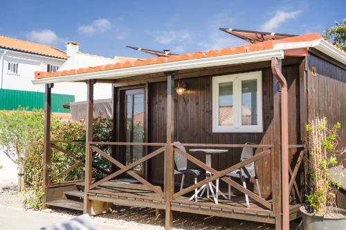 a wooden cabin with a porch and a chair at Pátio Mariano in Serra de El-Rei