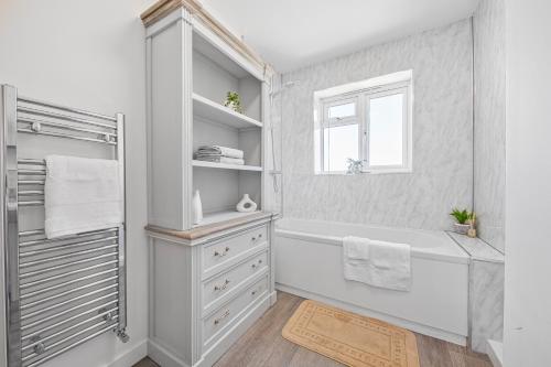 a white bathroom with a tub and a window at 2 Bed Flat 10mins Heathrow 1 Parking EV in Hanworth