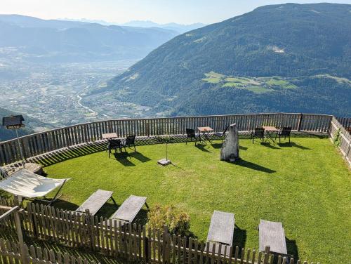 a field of grass with chairs and tables on top of a hill at Greiterhof Partschins in Parcines