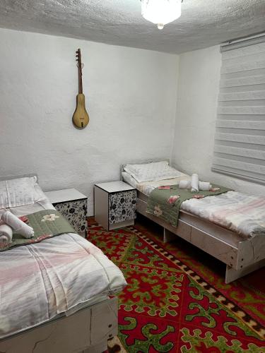 a bedroom with two beds and a guitar on the wall at Nazik Guest House in Barskoon