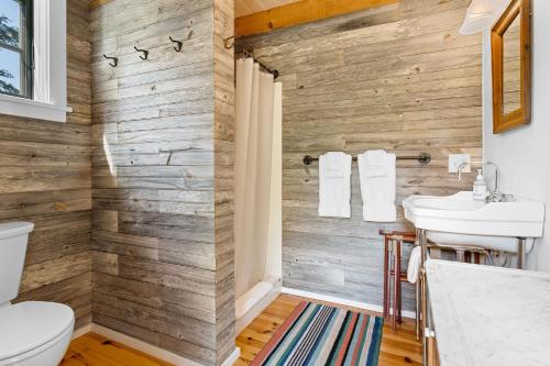a bathroom with a wooden wall at Aril Cottage-Waterfront Escape with Ocean Views in Gouldsboro