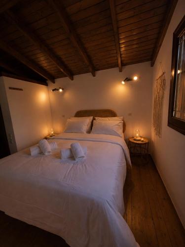 a bedroom with a large white bed with two pillows at Madona Casas in Psilá Alónia