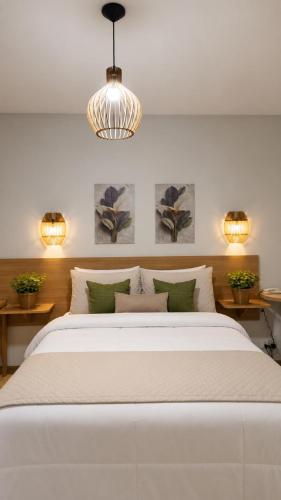 a bedroom with a large white bed and two lights at Vila Francesa Hotel in Penedo