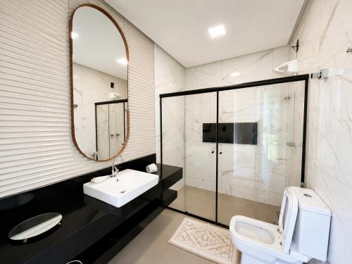 a bathroom with a sink and a toilet and a mirror at Pousada com piscina, jacuzzi e com vista em Capitólio - Casa Decore in Capitólio