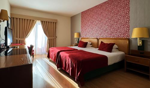 ein Hotelzimmer mit zwei Betten mit roter Bettwäsche in der Unterkunft Palace Hotel & Spa - Termas de Sao Vicente in Penafiel