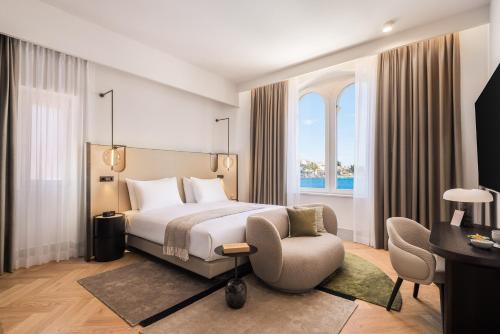 a hotel room with a bed and a chair at Aminess Younique Korcula Heritage Hotel in Korčula