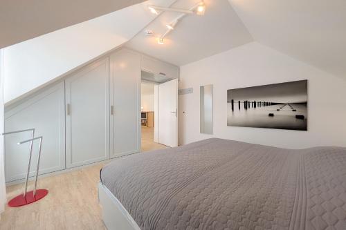 a white bedroom with a bed and a painting on the wall at Residenz Seestern Wohnung 32 in Boltenhagen