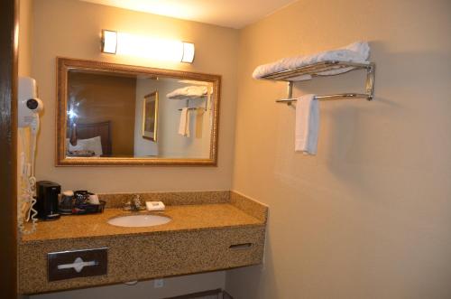 y baño con lavabo, espejo y toallas. en Regency Inn, en Chickasha