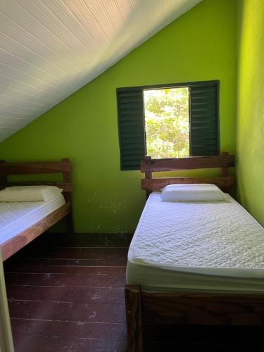 two beds in a green room with a window at Refúgio Mundo dos Pássaros in Sao Jorge