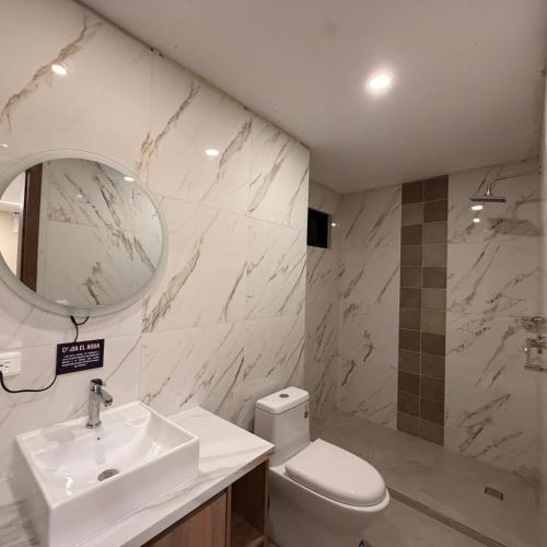 a bathroom with a sink and a toilet and a mirror at Hotel Ulloa Inn in Quito