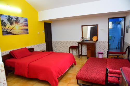 a bedroom with a red bed and a mirror at Jes Guest House in Majorda