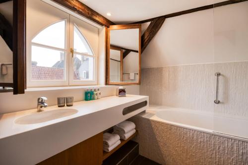a bathroom with a sink and a tub and a window at Crowne Plaza Hotel Brugge by IHG in Bruges