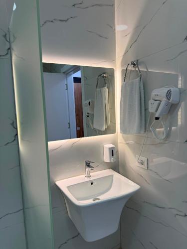a white bathroom with a sink and a mirror at Best House Albania in Kamëz