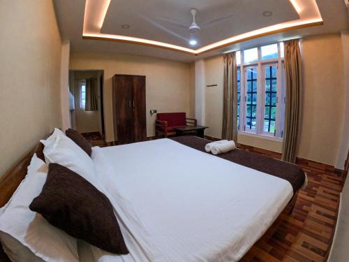 a bedroom with a large white bed with a window at Taleries Stays in Dirang Dzong