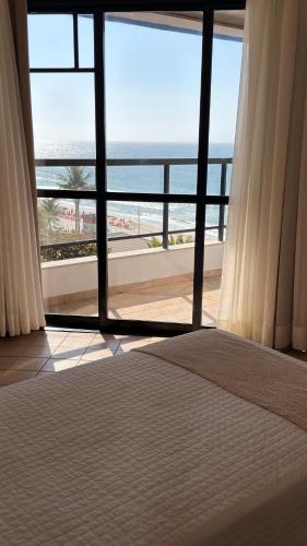 a room with a large window with a view of the ocean at Ingleses Praia Hotel - Com Piscina Aquecida in Florianópolis