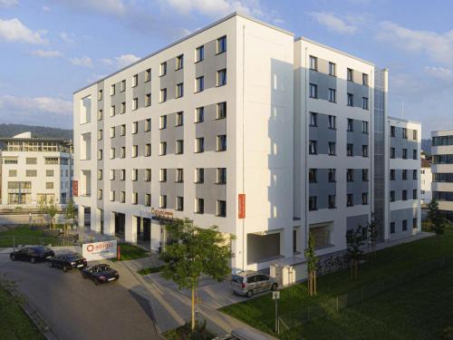 a white building with cars parked in front of it at Aparthotel Adagio Access Freiburg in Freiburg im Breisgau
