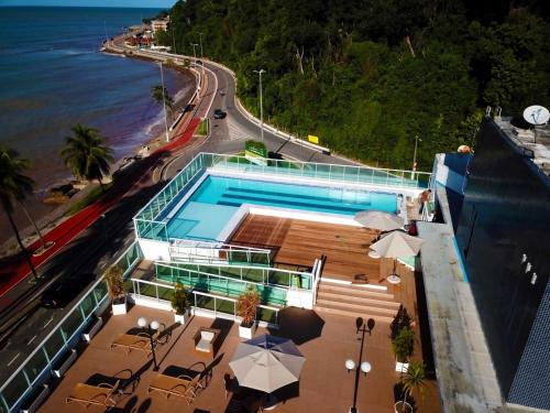 a swimming pool with umbrellas next to the ocean at Blue Sunset Experince - Cabo Branco in João Pessoa