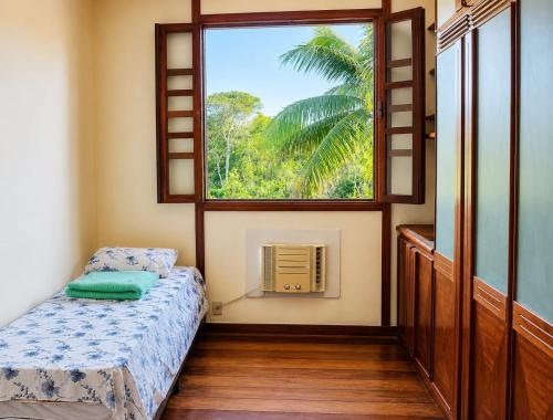 a bedroom with a bed and a large window at Casa Country Niterói in Niterói