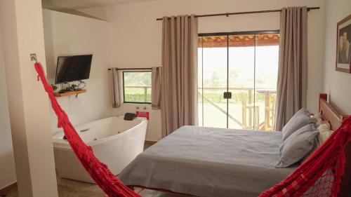 a bedroom with a hammock and a tub and a television at Chales Paraíso STL in São Thomé das Letras