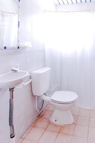 a white bathroom with a toilet and a sink at La Posada del Abra in Tigre