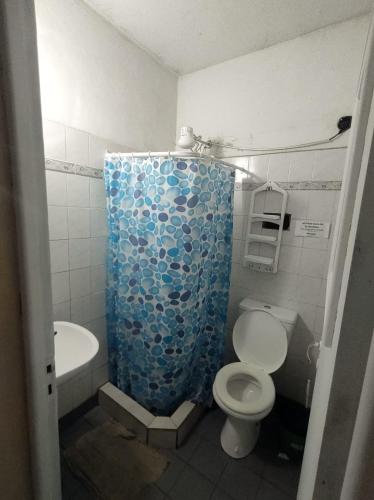 a bathroom with a toilet and a blue shower curtain at Como en casa Hostel in Posadas