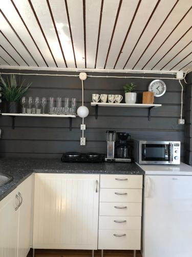 a kitchen with white cabinets and a wooden ceiling at Stuga Pörsvik in Nauvo