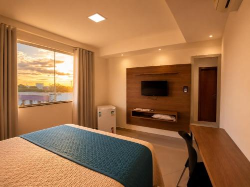 ein Schlafzimmer mit Bett, Fernseher und Fenster in der Unterkunft Hotel Skalla - MELHOR CUSTO BENEFICIO in Teixeira de Freitas