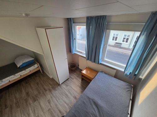 a small room with a bed and two windows at Holiday Hus in Rudkøbing