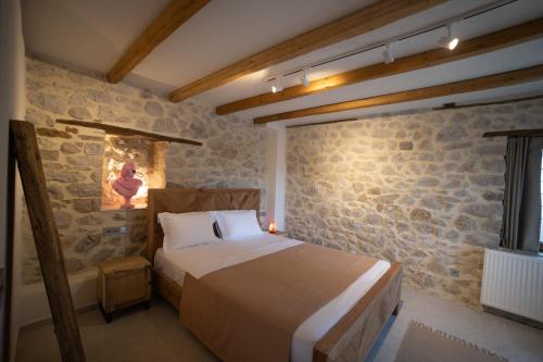a bedroom with a bed and a stone wall at Penelope Suites With View Meteora in Kalabaka