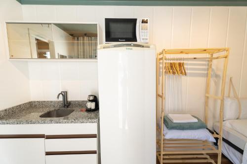 a small kitchen with a refrigerator with a microwave on top at Marco Zero Containers - Próximo à Roda Gigante in Balneário Camboriú