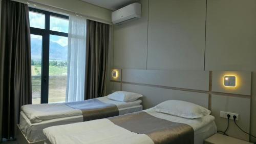 a hotel room with two beds and a window at Тынчтык Отель in Chon-Sary-Oy