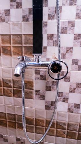 a shower with a hose attached to a wall at Jeks Apartments Limited in Ogbunike