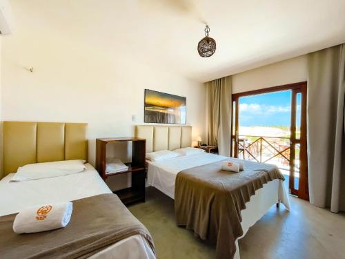 a hotel room with two beds and a balcony at Villa do Sol - Icaraí de Amontada in Icaraí