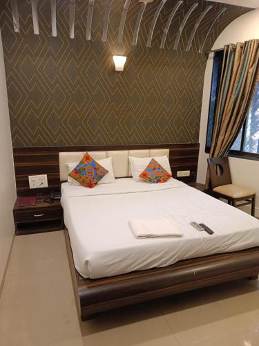 a bed with white sheets and pillows in a room at Crown Hotel Aadoree - Near Mumbai Airport, BKC Visa Consultant , Jio Convention Centre in Mumbai
