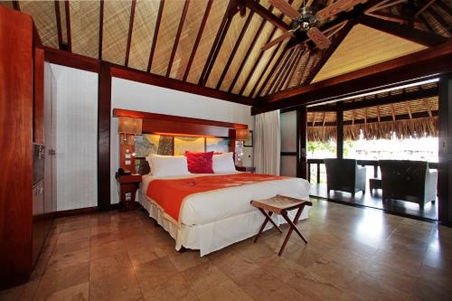 a bedroom with a large bed with red pillows at Sofitel Kia Ora Moorea Beach Resort in Maharepa