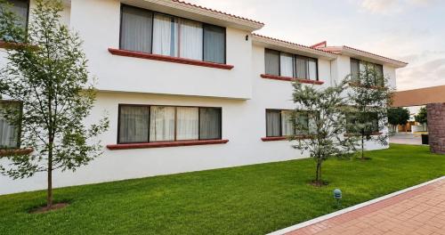 a white house with a green yard at La Posada Hotel y Suites in San Luis Potosí