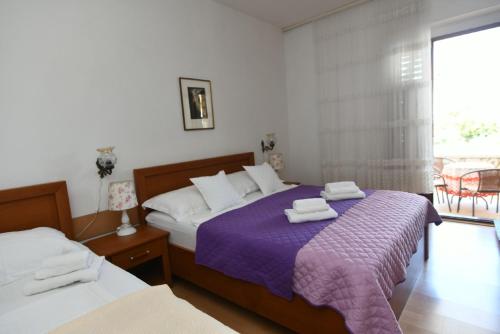 a bedroom with two beds with purple sheets and a window at Holiday Apartement Marija Supetar with private pool in Supetar