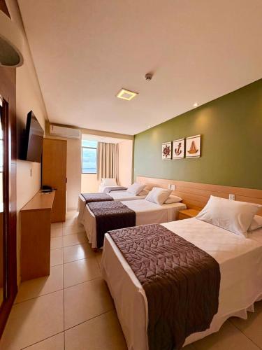 a hotel room with three beds and a television at Hit Hotel in Salvador