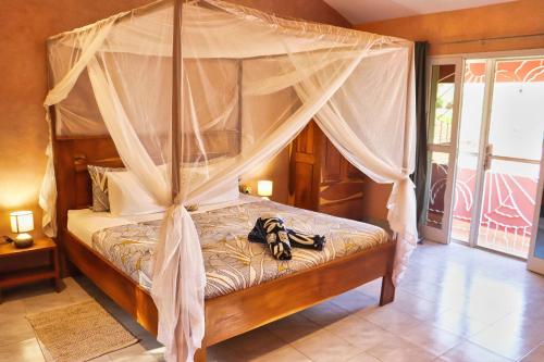 a bedroom with a canopy bed with shoes on it at Keur Noel in Ngaparou