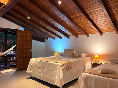 two beds in a room with wooden ceilings at Pousada Arraial Candeia in Arraial d'Ajuda