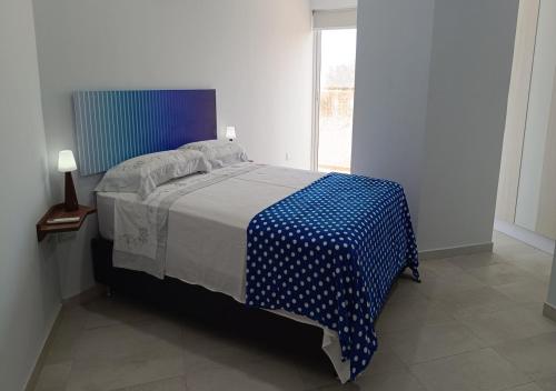 a bedroom with a bed with a blue and white blanket at Yaque Breeze - Beach Apartament in El Yaque