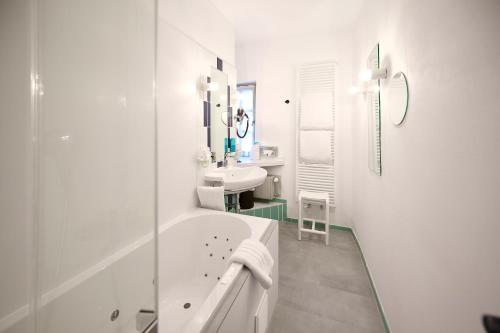 a white bathroom with a tub and a sink at Restaurant & ****Hotel HÖERHOF in Idstein