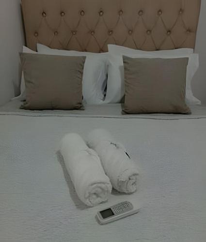 a pile of towels on a bed with a remote control at Apartamento próximo a Lagoa do Perola in Governador Valadares