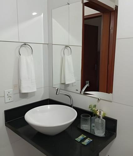 a bathroom with a large white sink on a black counter at Apartamento próximo a Lagoa do Perola in Governador Valadares